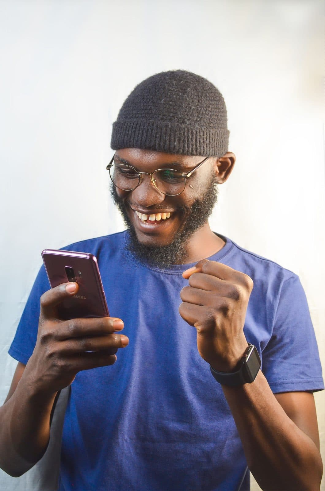 A young man grinning at good news on his phone